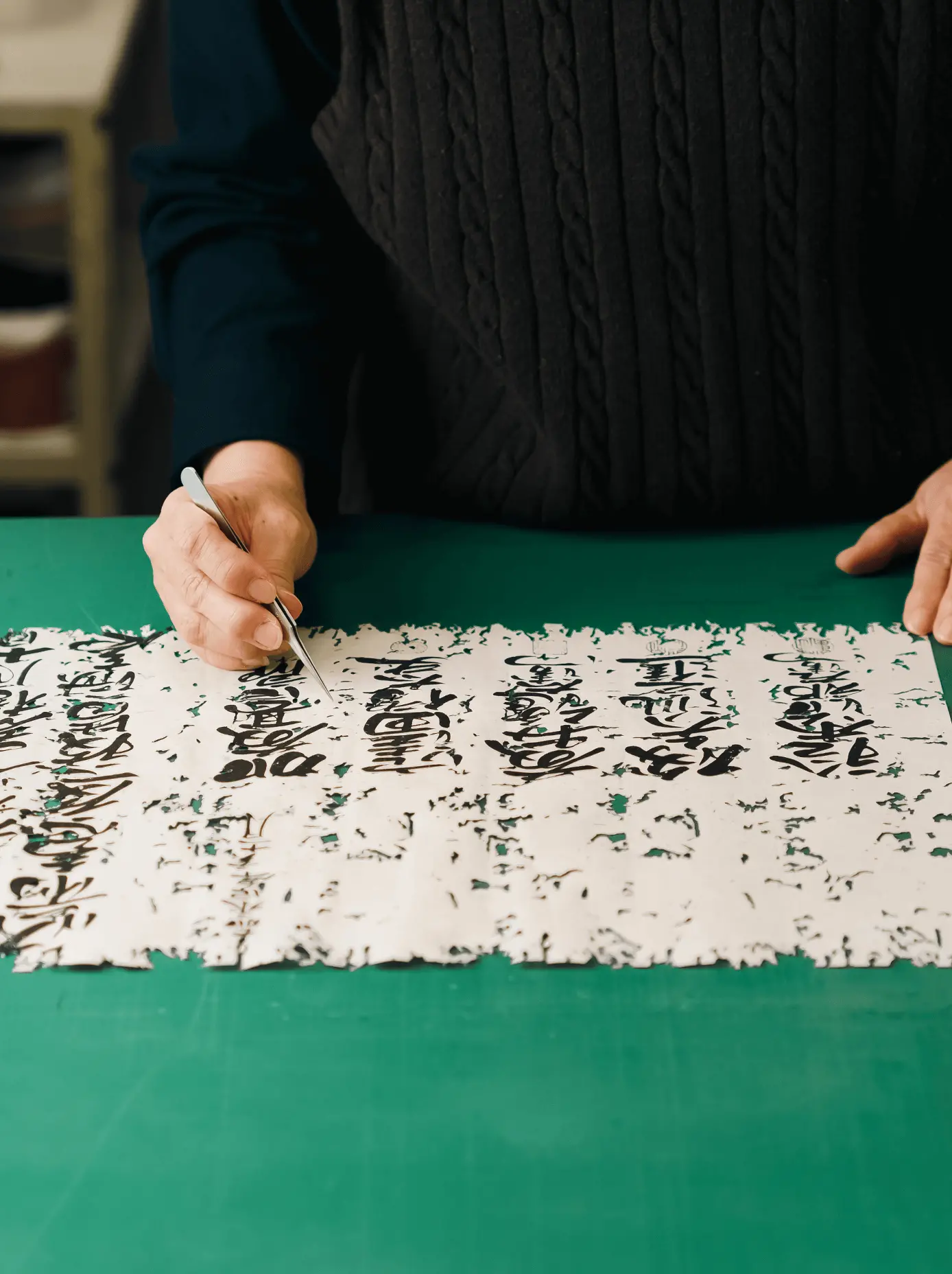 修復途中の古文書を作業台に広げ、文字部分を確認しながら紙の欠損や剥離を補修している表具師の作業風景。古文書修復を専門とする三重県伊勢市の株式会社辻村表具店の職人技