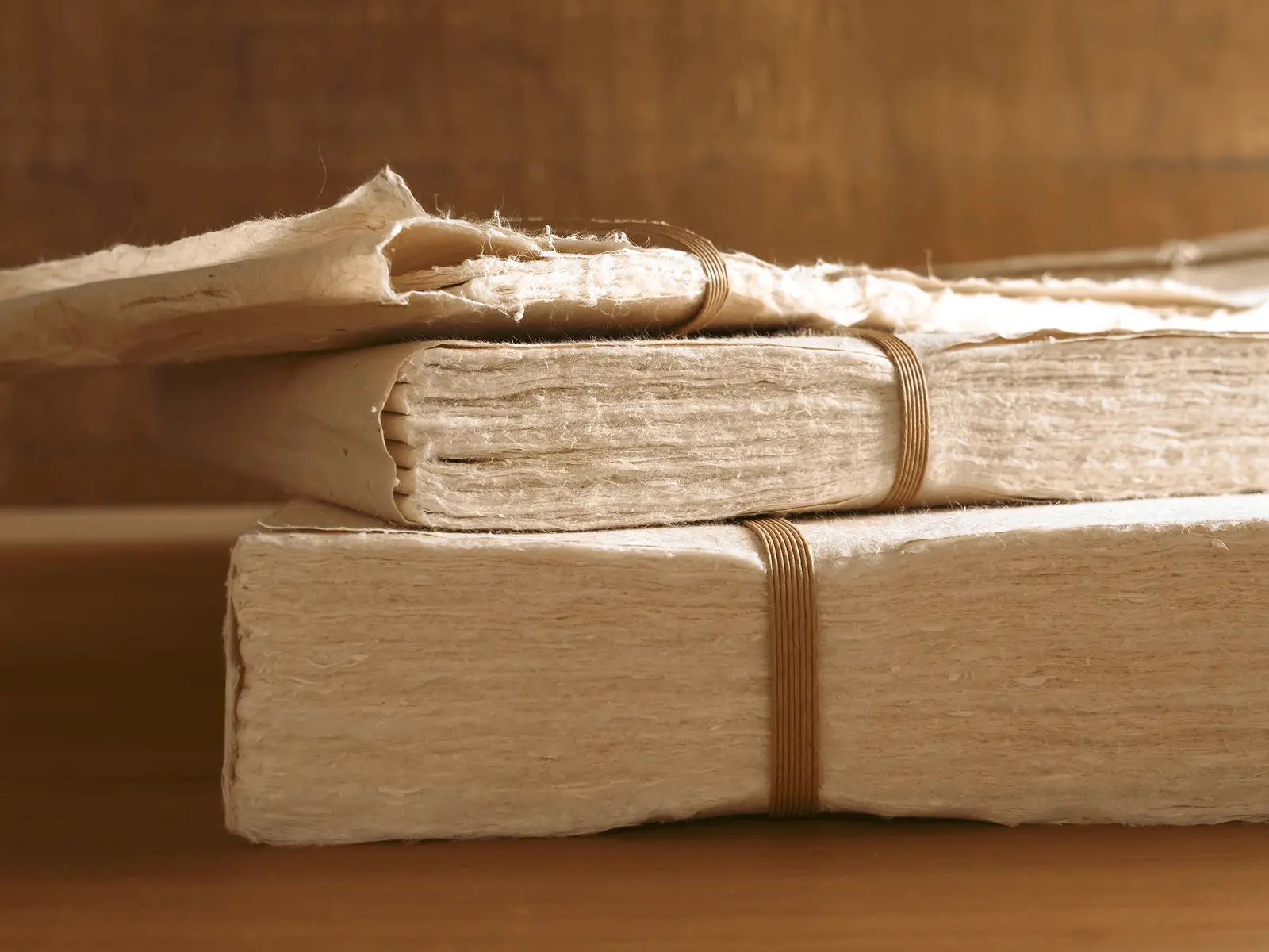 厚みの異なる手漉き和紙を重ねて束ねた状態を横から見た写真で、掛け軸や古文書修復に使われる和紙の繊維の層や質感が確認できる