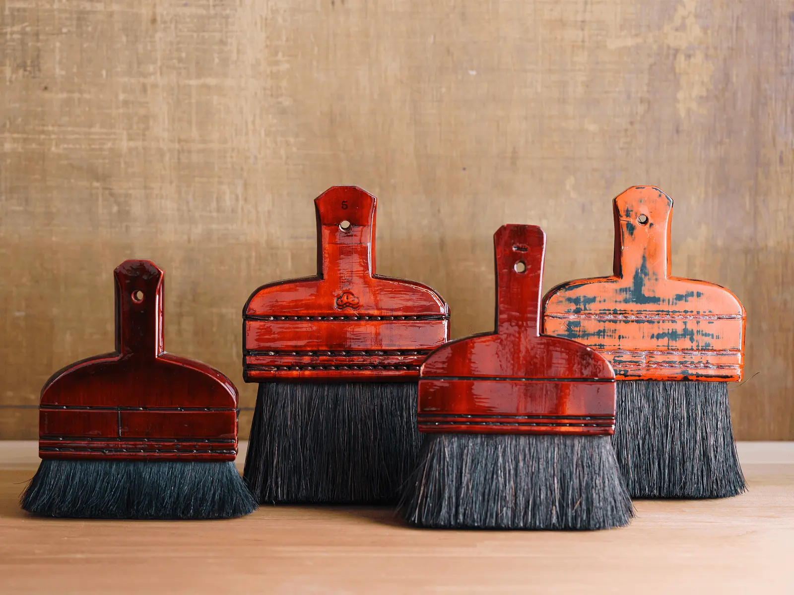 朱塗りの表装用刷毛が複数本並べられており、掛け軸や襖の裏打ち作業で糊を均一に塗布するための伝統的な道具であることが分かる