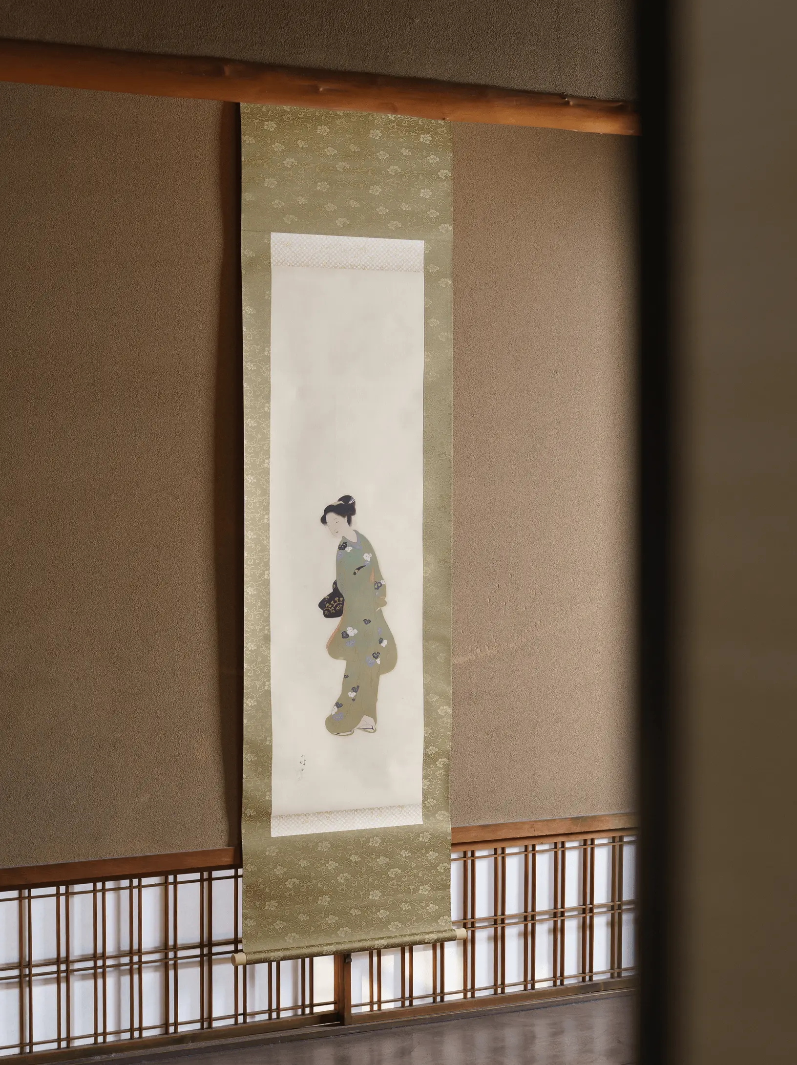 和室の床の間に掛けられた美人画の掛け軸。淡い色合いの着物を着た女性が描かれており、伝統的な表装技術と掛け軸修復による仕上がりの美しさが分かる展示風景。