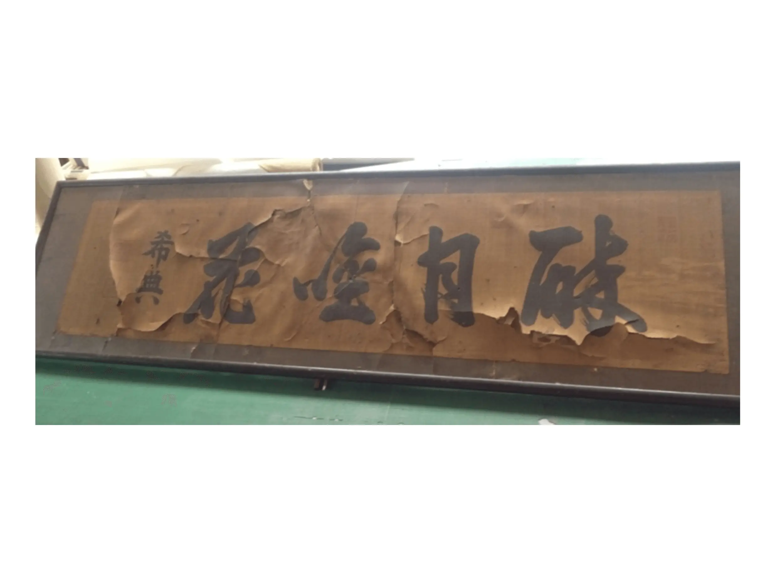 修復前の書作品の表題部分。紙が大きく剥落し、文字の周囲に破れや浮きが発生している状態で、経年による劣化が著しい掛け軸の一部。掛け軸修復、書画修理の施工前記録。