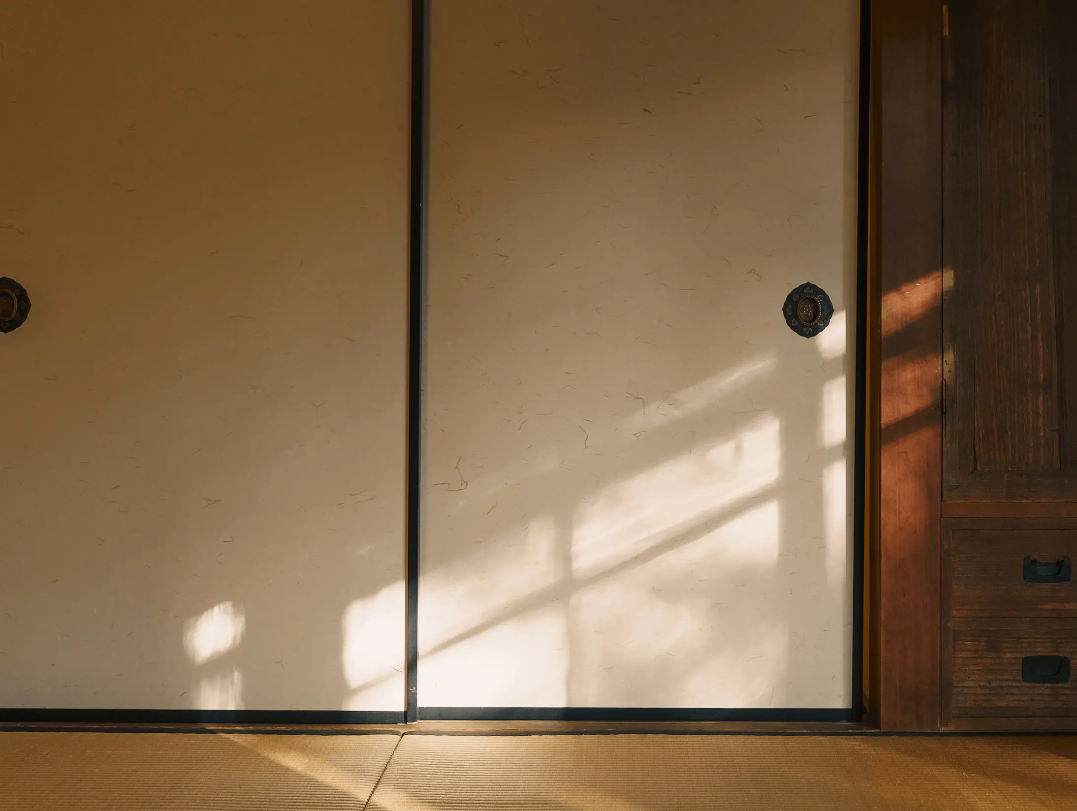 夕方の自然光が差し込む和室の襖の写真。修復・張替え後の襖紙に柔らかな光と影が映り込み、和室空間の落ち着いた雰囲気と日本建築における襖修理・建具修復の仕上がりの美しさが伝わる。