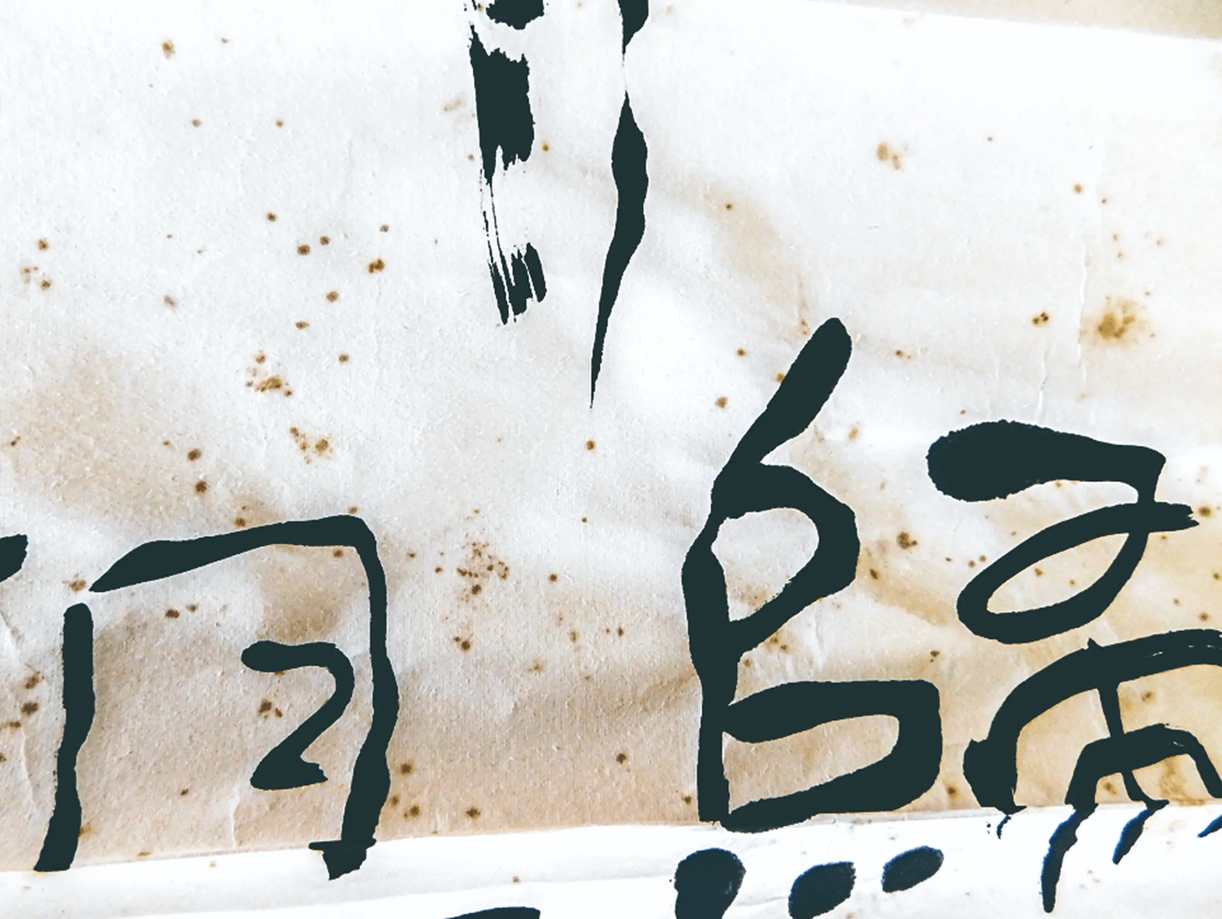 和紙に墨で書かれた「帰る」の文字のクローズアップ。経年劣化により茶色く変色した和紙の質感と毛筆による力強い筆致が見える掛け軸の一部