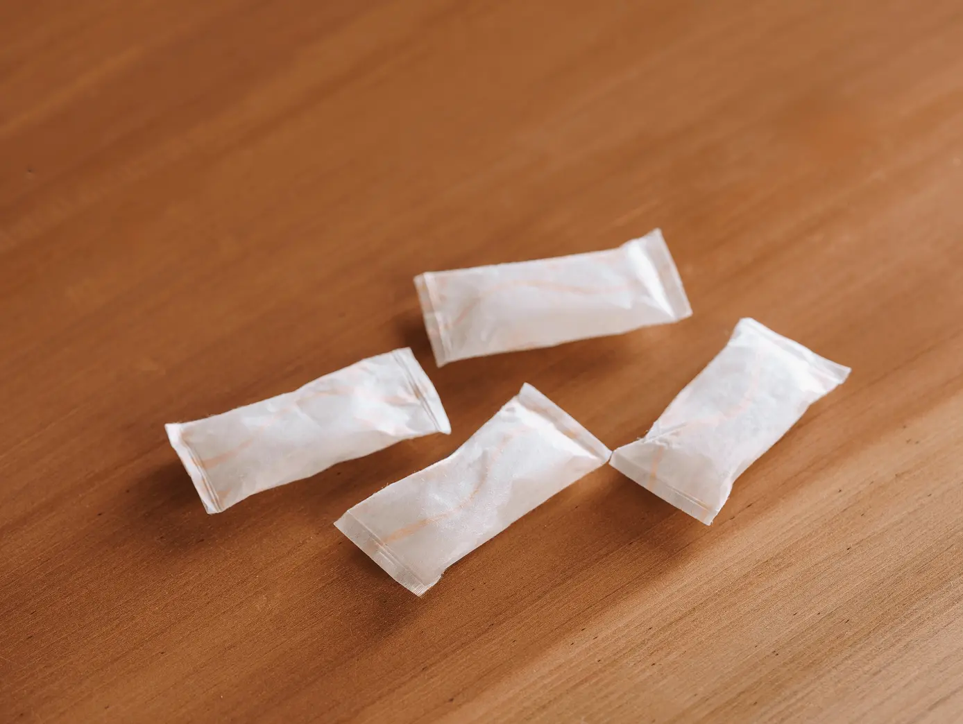 木製テーブルの上に置かれた4つの白い個包装の防虫剤パック。表具や掛け軸の保管に適した専用防虫剤
