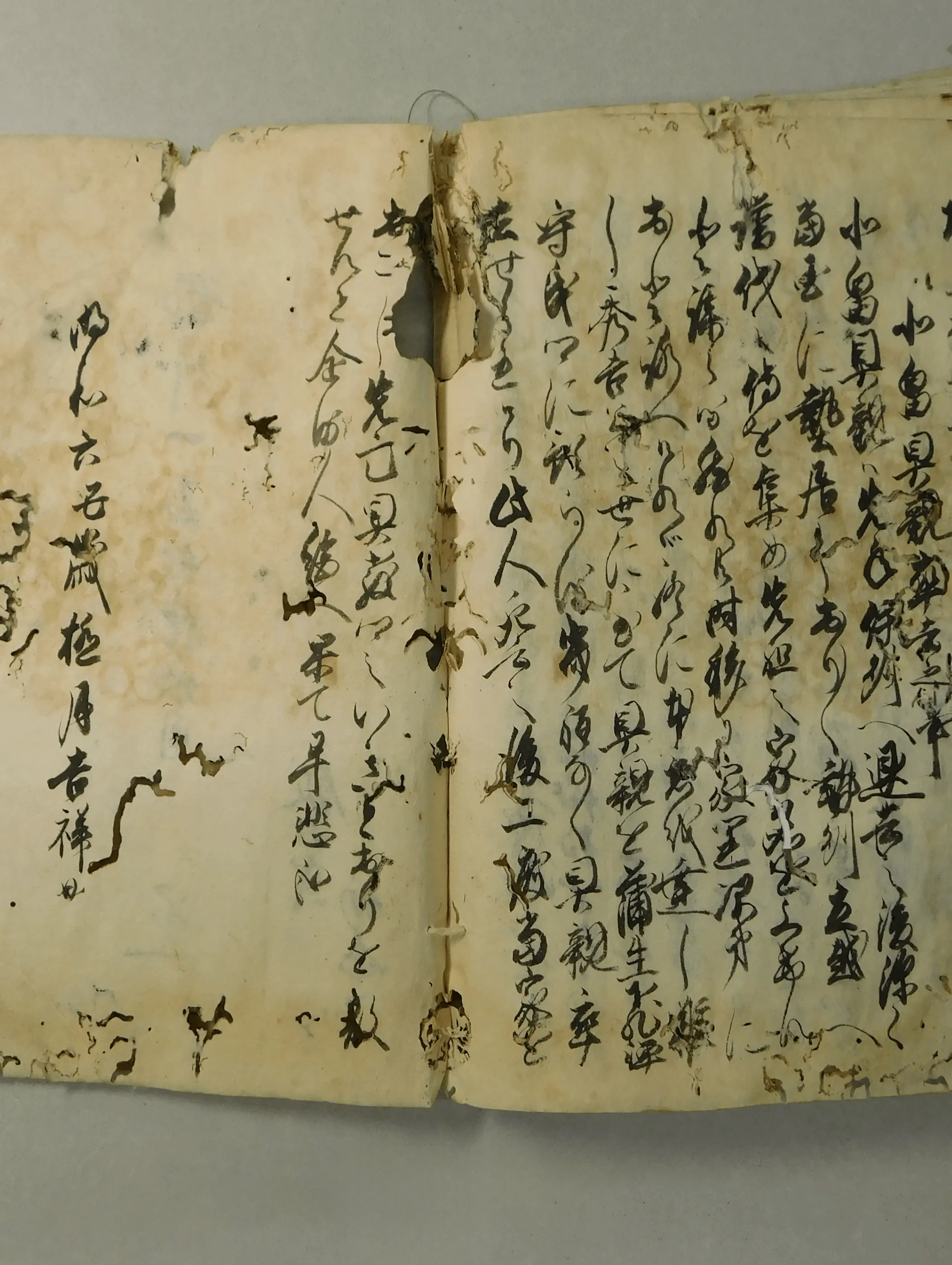 破れや虫損、汚れが広がった修復前の古文書の見開きページで、紙の劣化や欠損が進んだ状態が分かる資料を撮影したもの。三重県伊勢市の株式会社辻村表具店による古文書修復前の記録