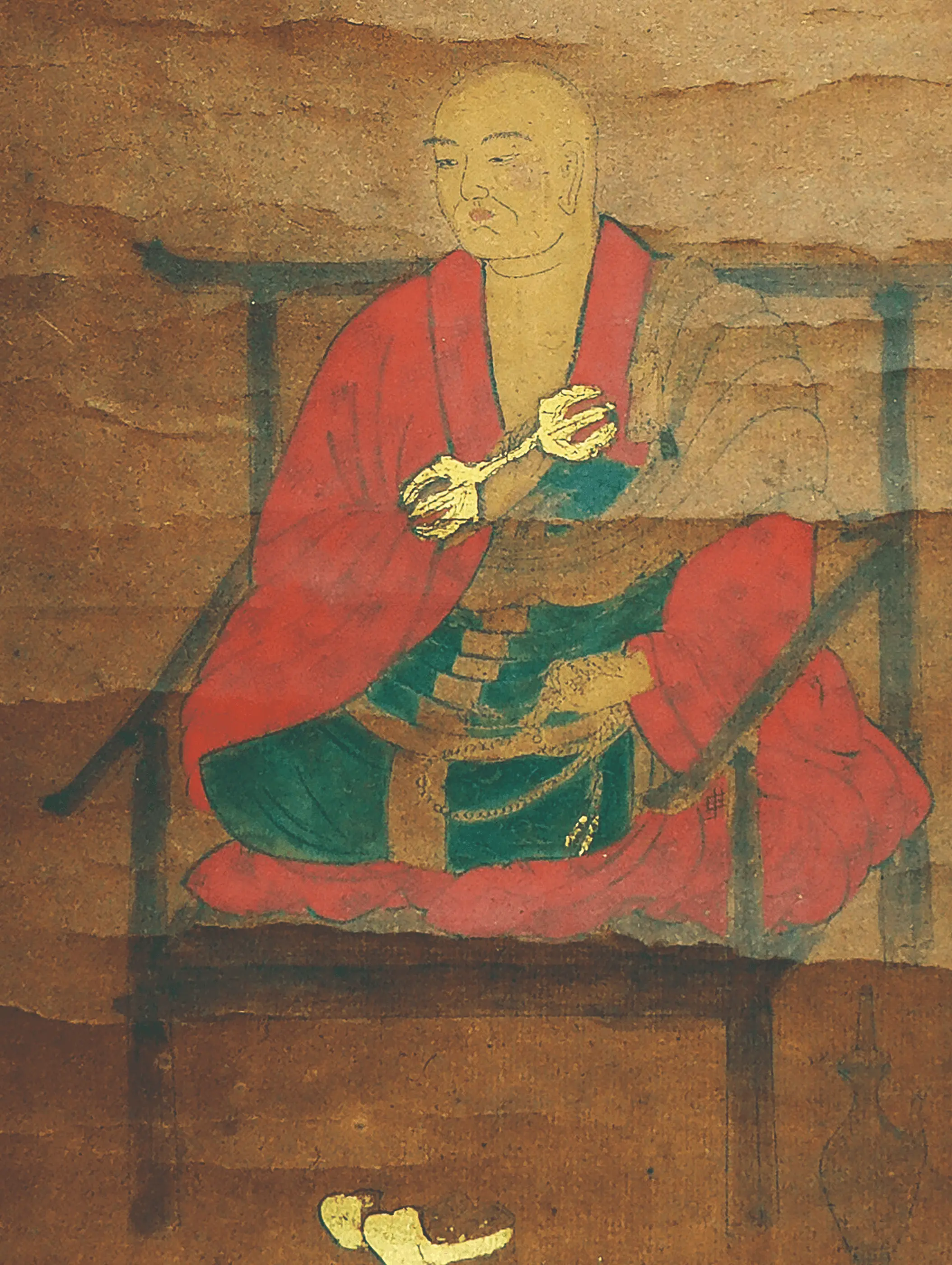 経年劣化した掛け軸の一部に描かれた僧侶像の修復前の状態で、顔料の退色や紙地の汚れ、表面の荒れが見られる日本画の古い作品。株式会社辻村表具店（三重県伊勢市）の修復対象資料